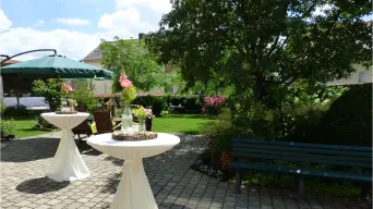 Der Garten und der Hof mit weißen Stehtischen im Sommer bei schönem Wetter. Landhaus Odaia