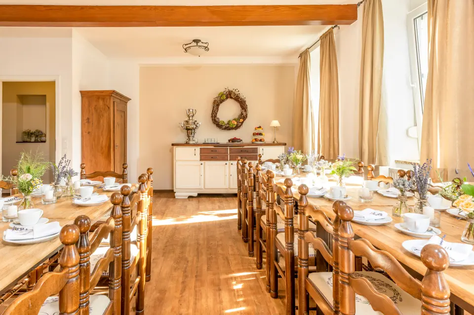 Eingedeckter Raum im Stübchen mit Holztischen, Blumendekoration und Tageslicht