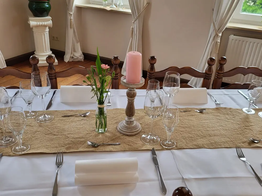 Geschmackvoll dekorierter Tisch mit einer Kerze, Blumenvase und einem rustikalen Jute-Tischläufer im Salon, Landhaus Odaia.